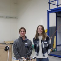 Two students standing next to a fourth block elevator project.